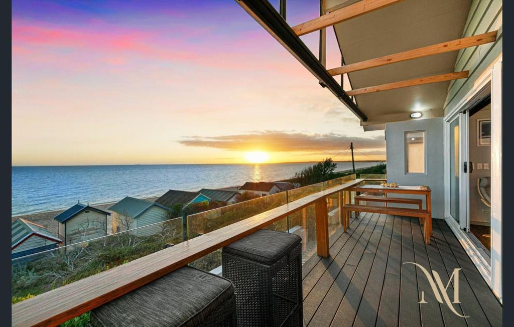 a balcony with a view of the ocean at sunset at Gate Access to the Beach in Edithvale