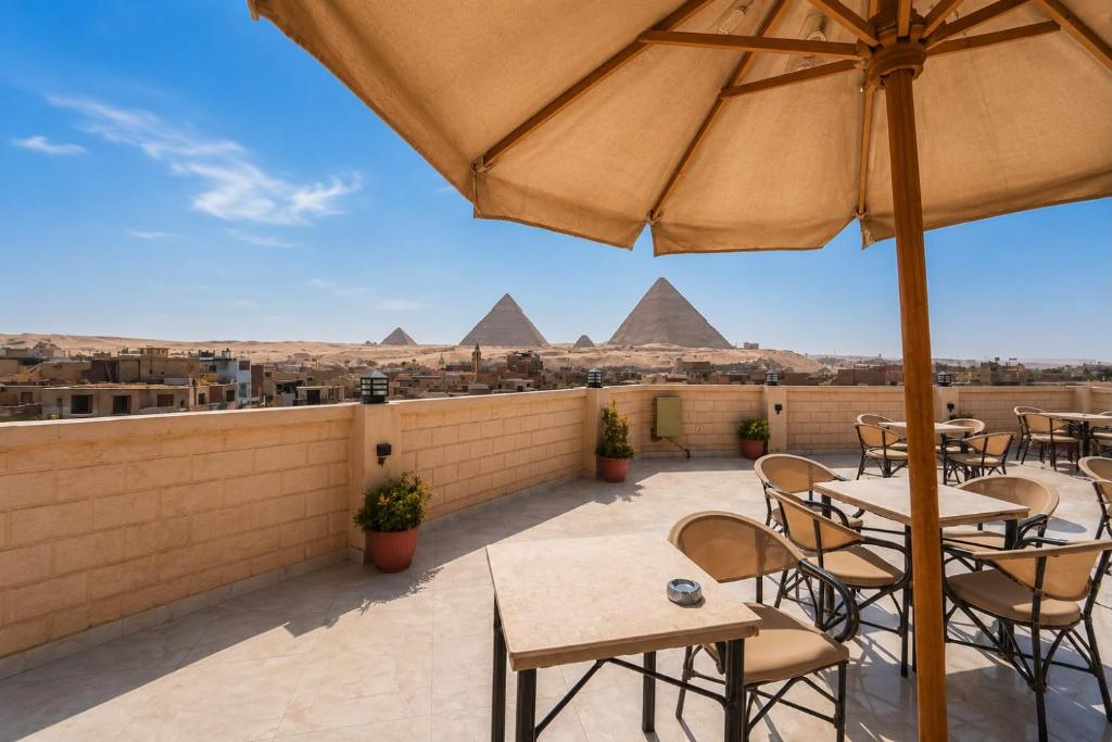 a patio with tables and chairs and the pyramids at Golden RZ pyramids view in Cairo
