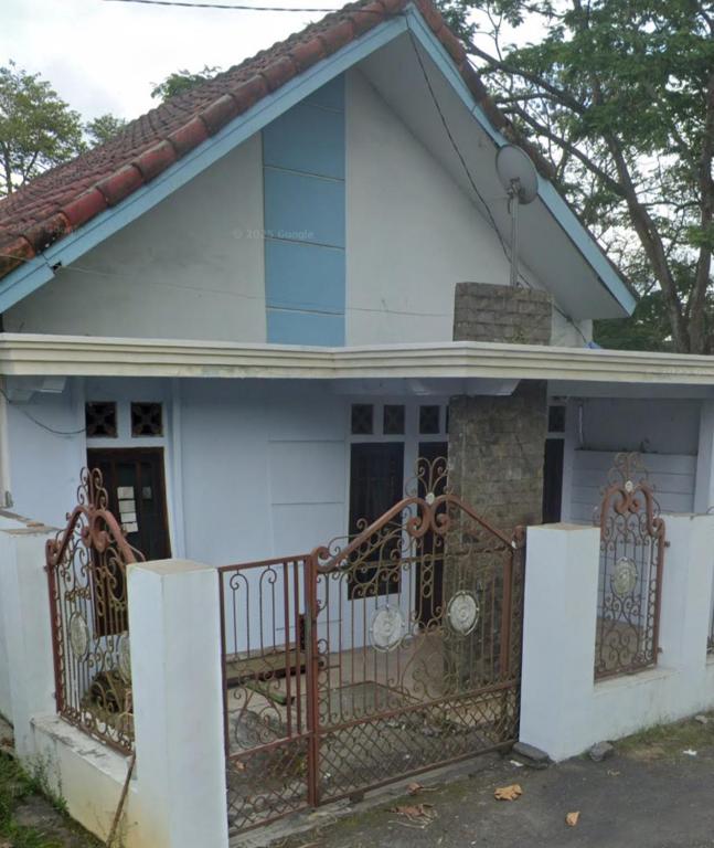 a white house with a gate in front of it at River cliff guest house in Gunungsriti