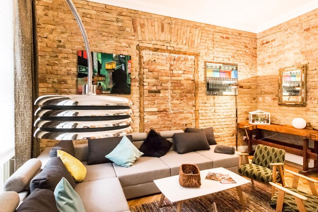 Una sala de estar con un sofá y una pared de ladrillos. en Urbana Hipster Downtown Budapest, en Budapest