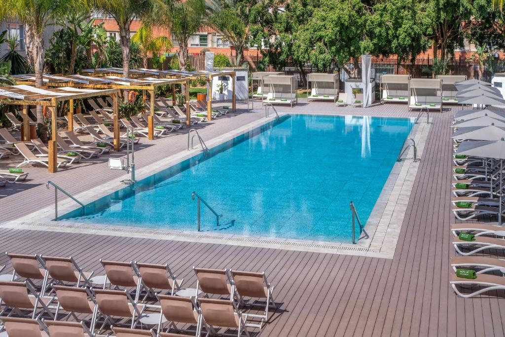 a large swimming pool with chairs and tables at Meliá Lebreros in Seville