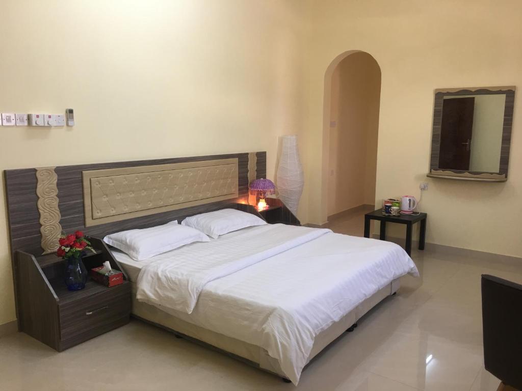 a bedroom with a large bed with white sheets at Stone Guest House in Al ‘Aqar