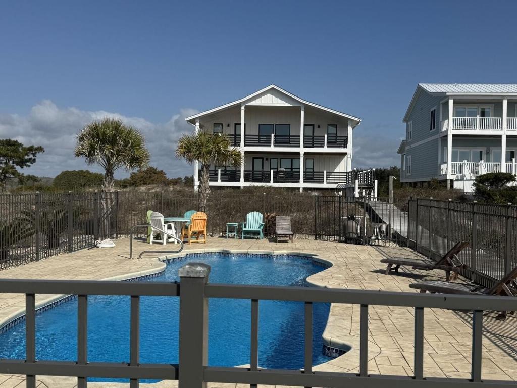 a swimming pool in front of a house at Somewhere South home in Holden Beach