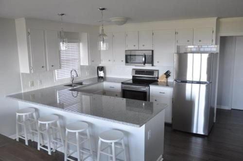 a kitchen with a refrigerator and a counter with bar stools at Dune Deck South - Duplex in Holden Beach