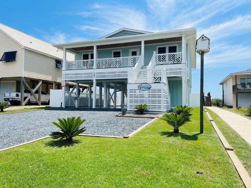 a white house with a balcony and a yard at Holden R Breath in Holden Beach