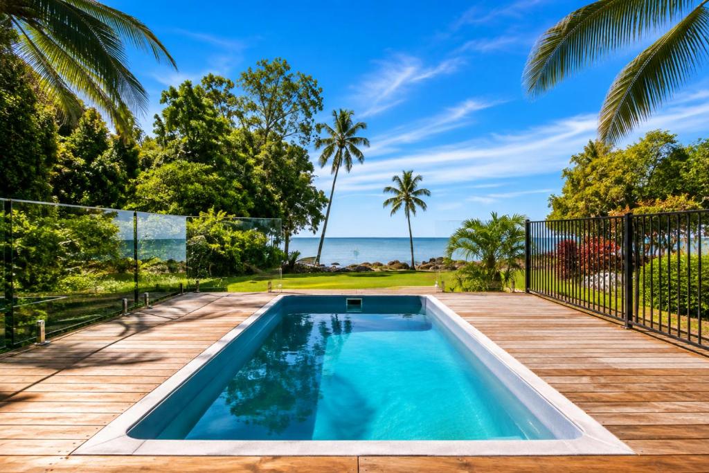 a swimming pool on a deck with the ocean in the background at Cairns Beachfront Retreat in East Trinity