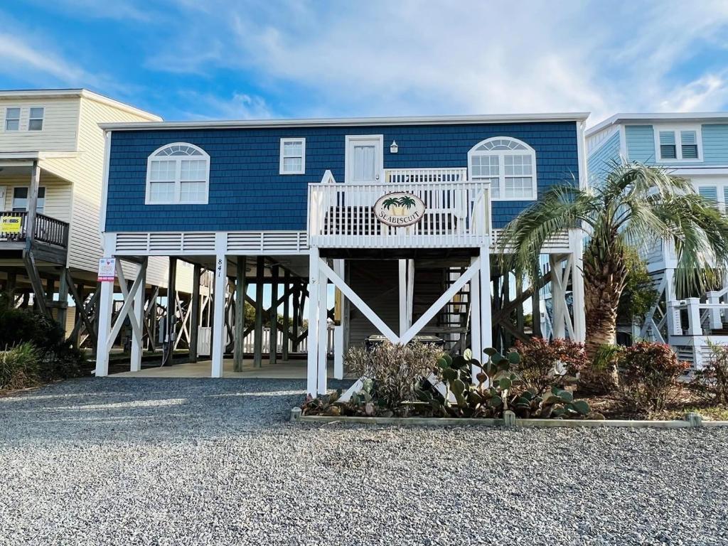 a blue house with a white front porch and a porch at Sea Biscuit in Holden Beach