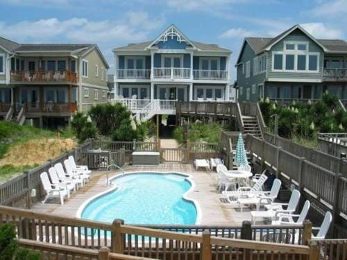a large house with a swimming pool and chairs at Majak Moments in Holden Beach