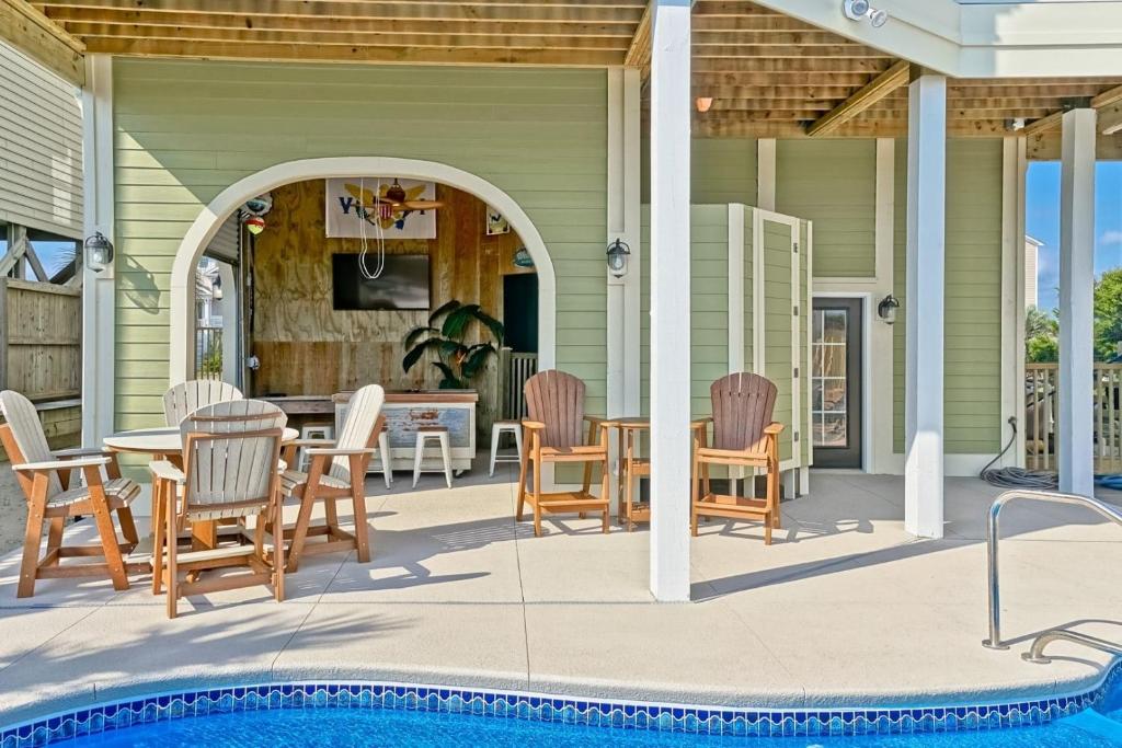 a patio with a table and chairs next to a pool at Cinnamon Sands home in Holden Beach