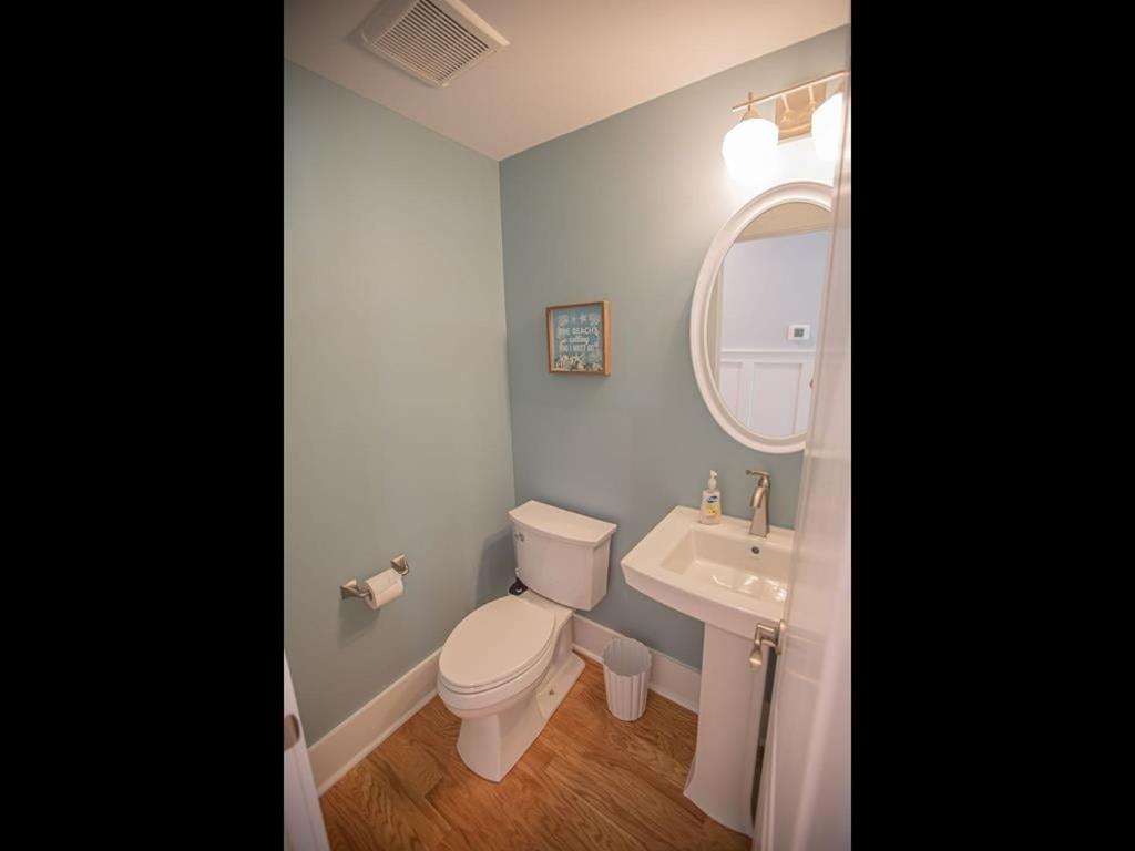 a bathroom with a toilet and a sink and a mirror at The Sandbox home in Holden Beach