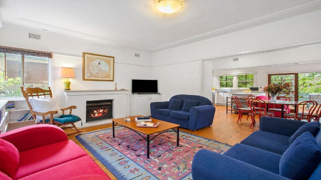 a living room with blue and red furniture and a fireplace at King Parrot Cottage - Close To Beach in Pearl Beach