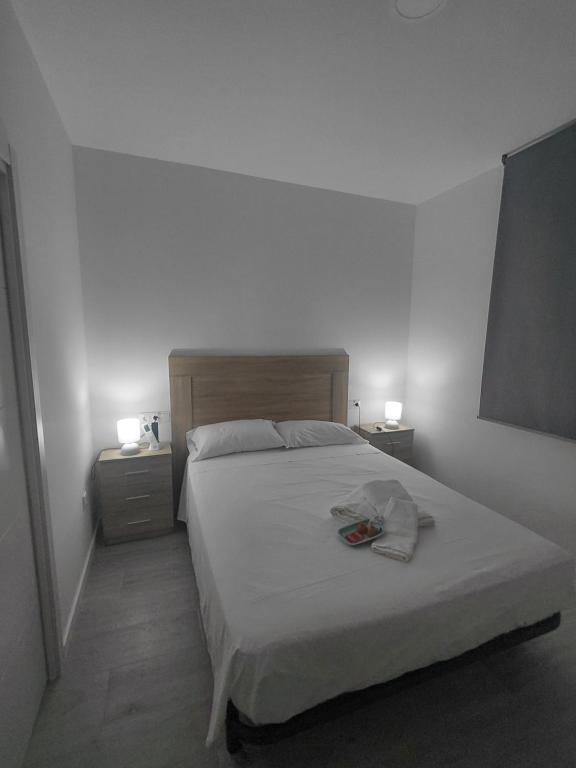 a white bedroom with a bed with two night stands at Corvera Guss in Corvera