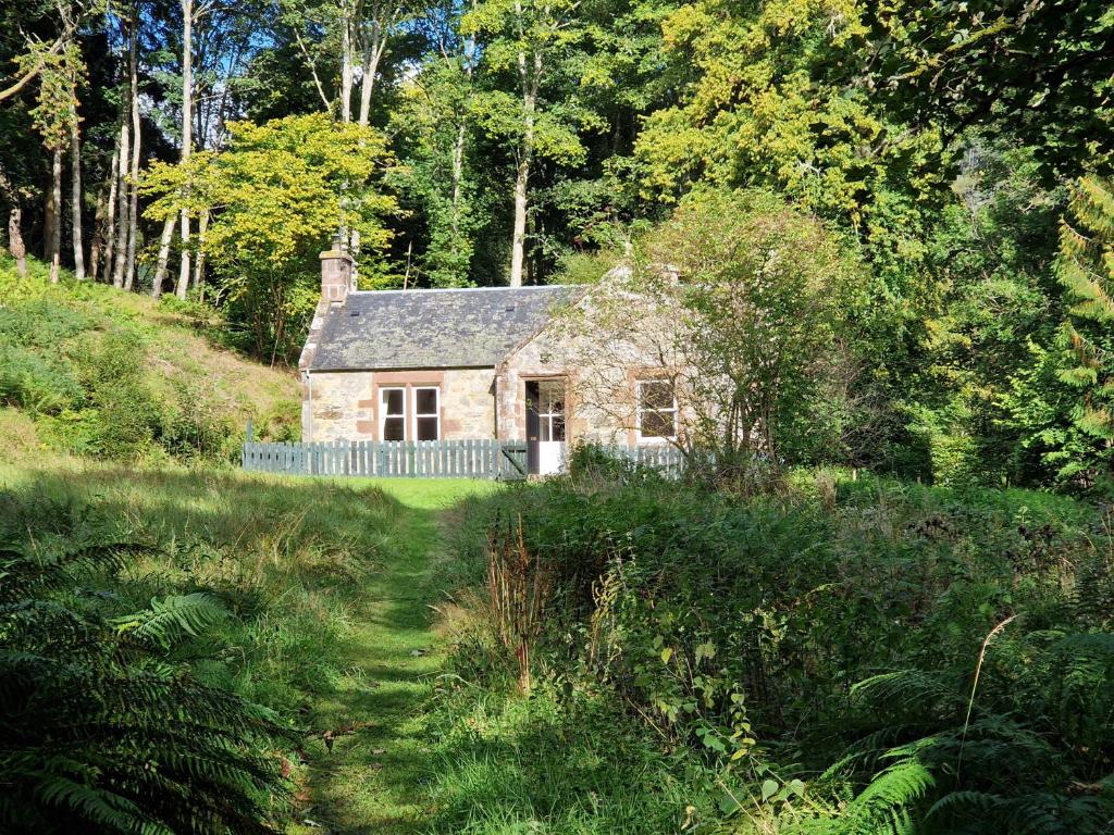 a small stone house in the middle of a field at Gunroom Cottage in Strathpeffer
