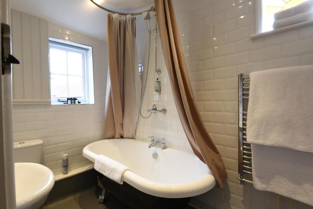 a bathroom with a sink and a tub and a toilet at Sutherland House in Southwold