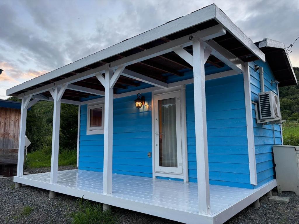 a blue house with a white porch at Ehana Cofee Roastery Hanare in Kami-furano