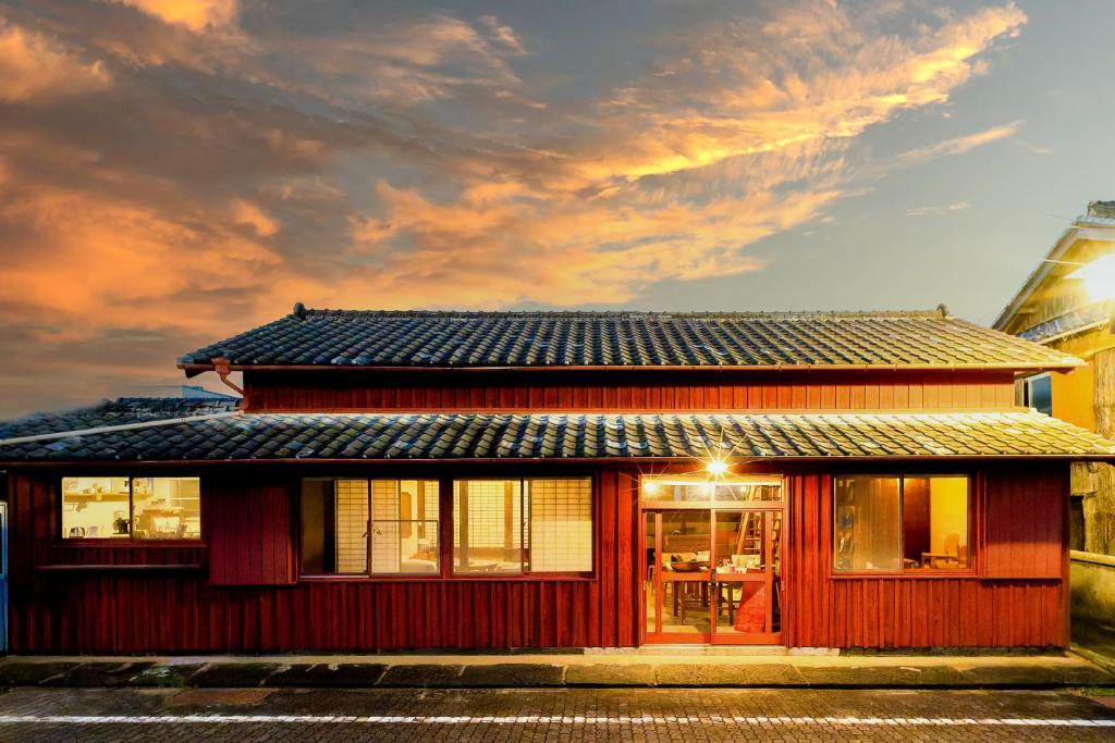 a red building with a dark roof on a street at 泊れる図書館 さんごさん in Goto