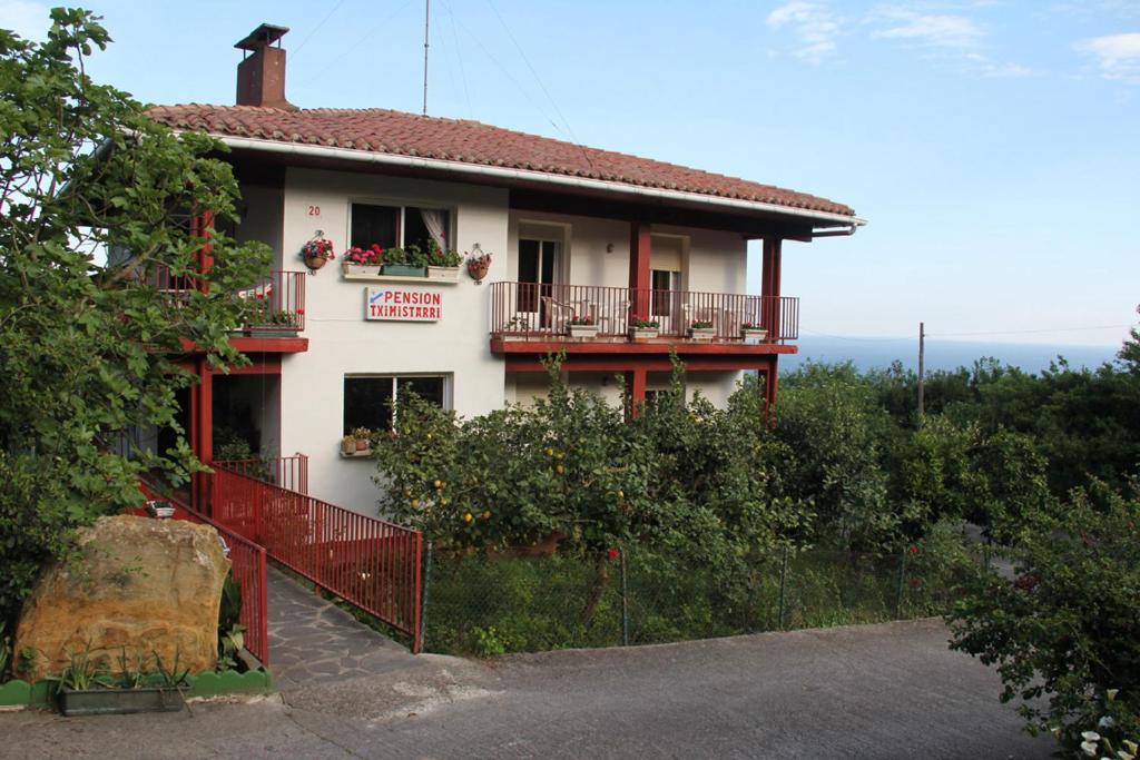 Casa blanca con balcón y valla en Pensión Tximistarri, en San Sebastián