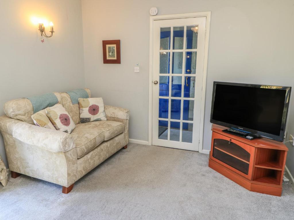 ein Wohnzimmer mit Sofa und Flachbildfernseher in der Unterkunft Lamora in Cheddar