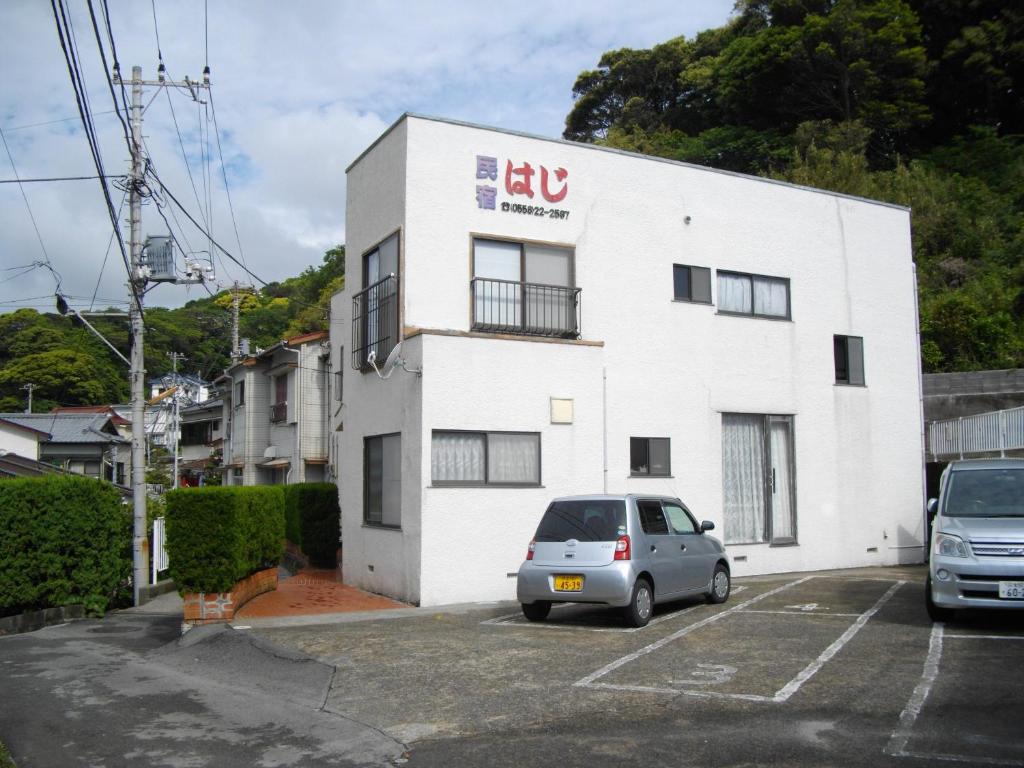 un edificio blanco con un coche aparcado en un aparcamiento en Minshuku Haji, en Shimoda