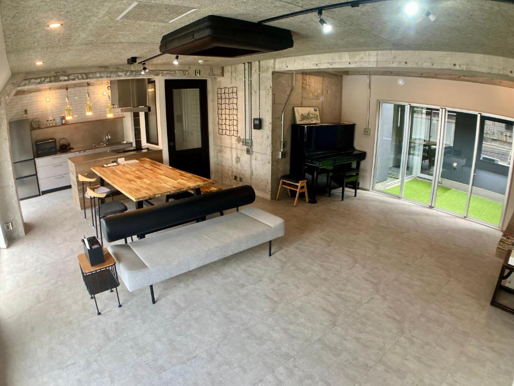 a living room with a table and a piano at Guesthouse Matsu 別館 in Osaka