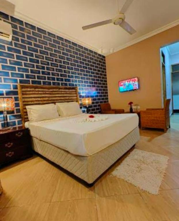 a bedroom with a large bed with a brick wall at Paradiso Hotel in Dar es Salaam