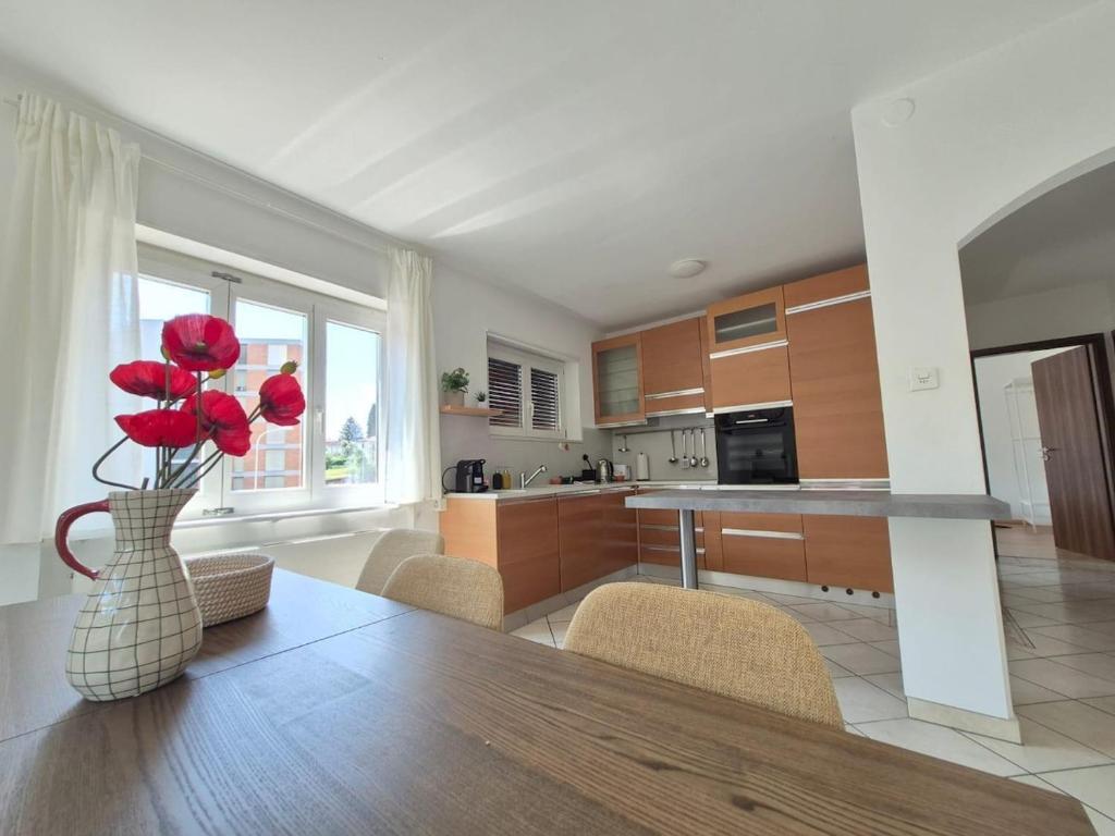 a kitchen with a table and a vase with red roses at Sunlit Lugano & Parking Free in Massagno