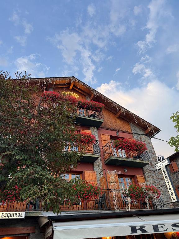 a building with red flowers on the balconies at Hotel Esquirol in Llivia