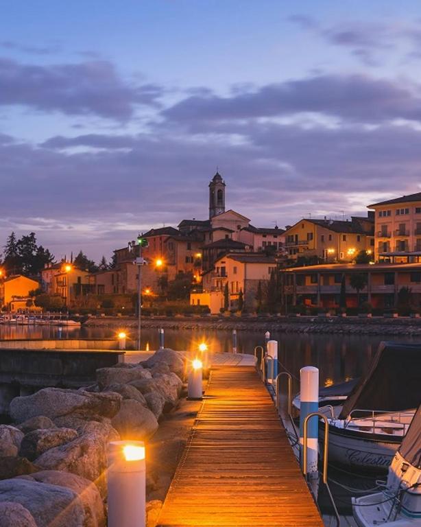 a wooden dock with lights on the water at night at CASA SMERALDO - LIGHT BLUE in Clusane sul Lago