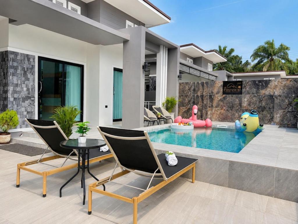a house with a swimming pool with two chairs and a table at The Phuview Pool Villa Aonang in Ban Chong Phli