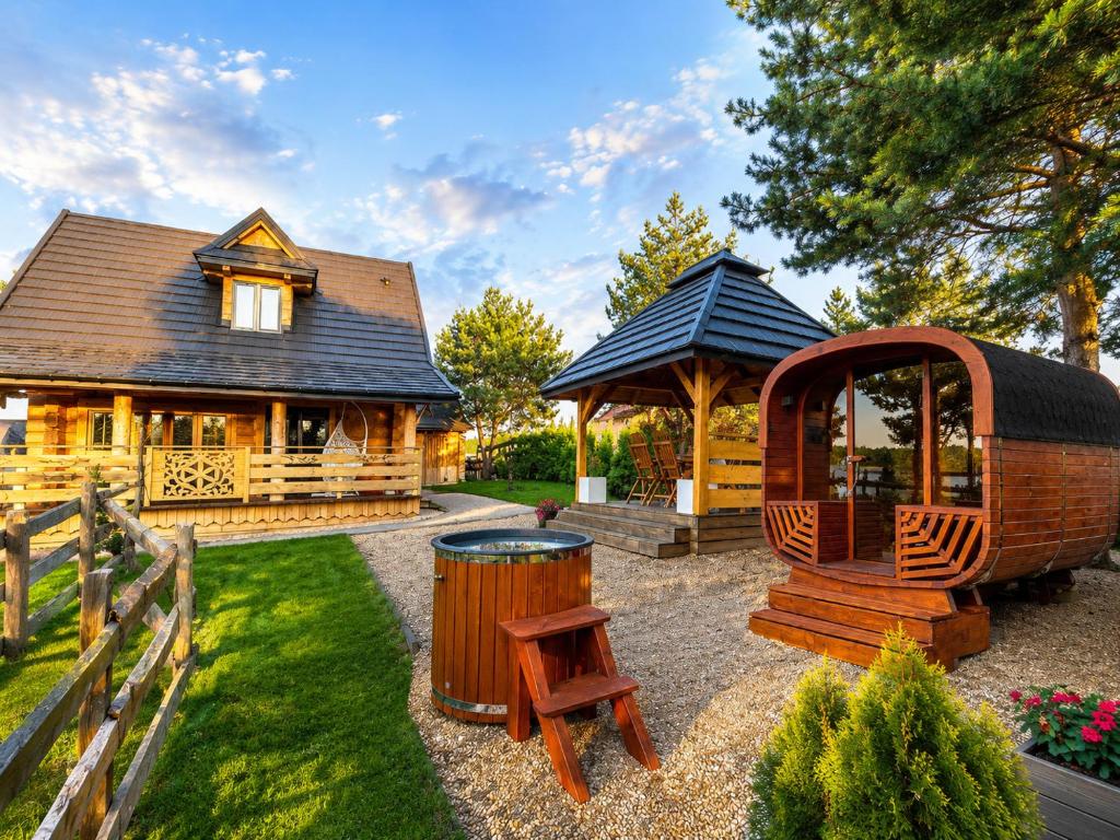 a log cabin with a gazebo and a bench and a barrel at Mazury "Willa Ślimakowo" w Pasymiu - jacuzzi, sauna, pomost, łódka, rower wodny - wolne od 23 sierpnia in Pasym