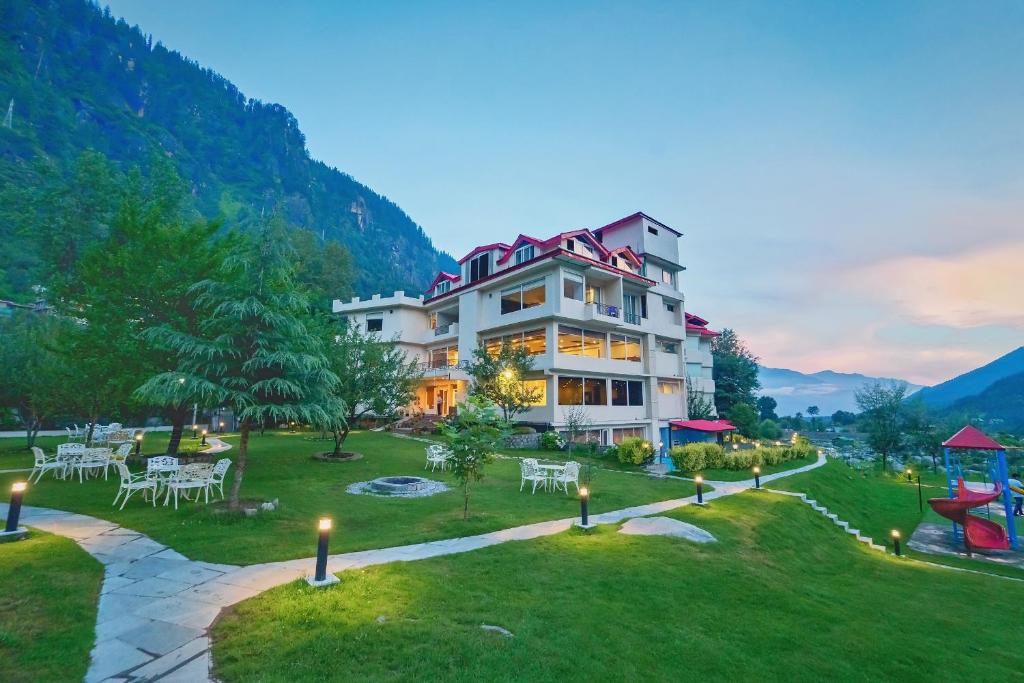 a building with tables and chairs in a park at The Allure Grand - Riverside Resort & Spa in Manāli