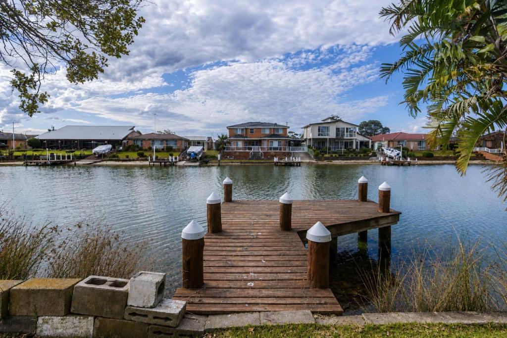a wooden dock in the middle of a lake with houses at Waterfront Delight on Cater in Sussex Inlet