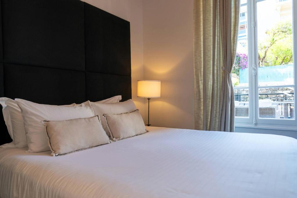 ein Schlafzimmer mit einem großen weißen Bett und einem Fenster in der Unterkunft Hotel De Monaco in Cap d'Ail