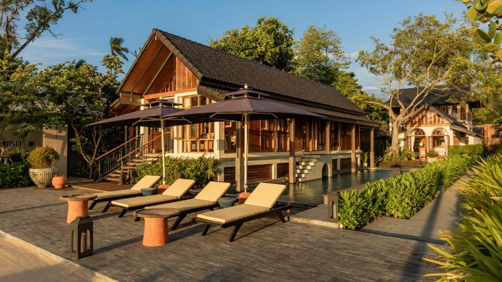 a group of chairs and an umbrella in front of a house at Siritarar Residence by Elite Havens in Nathon Bay