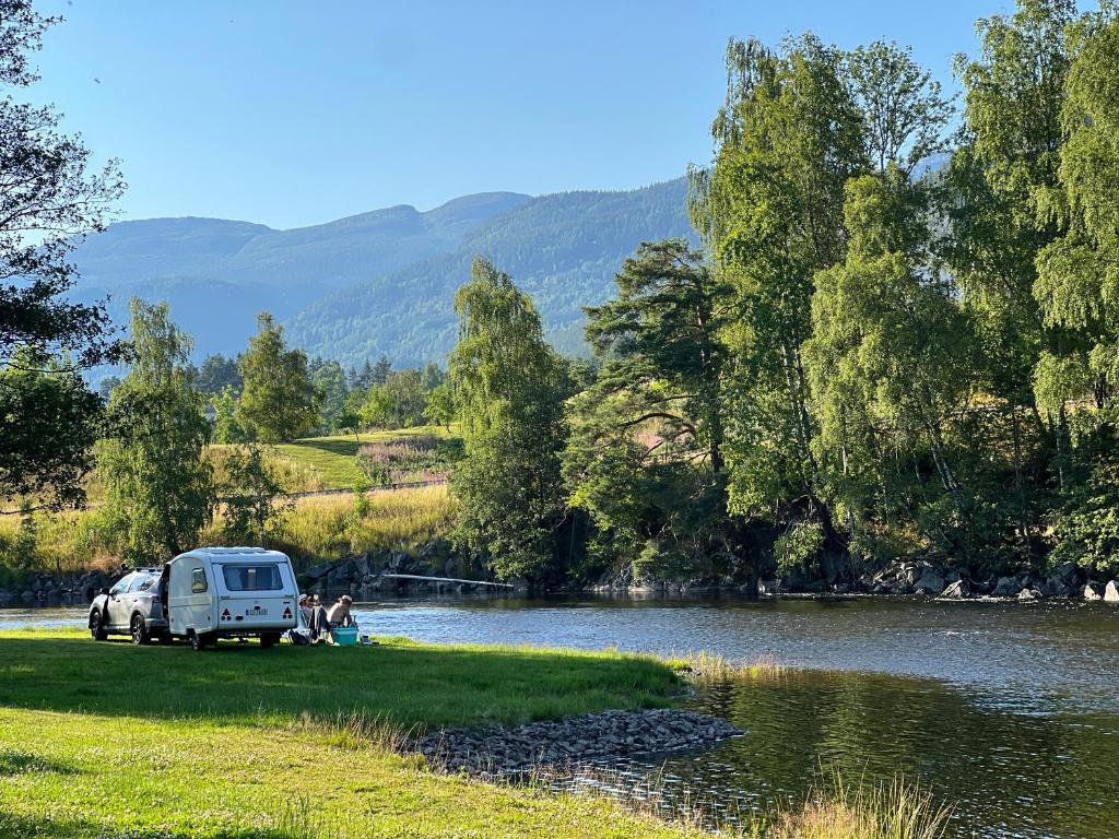 a camper van parked next to a river at Sanda Camping og Hytteutleie in Øvrebø
