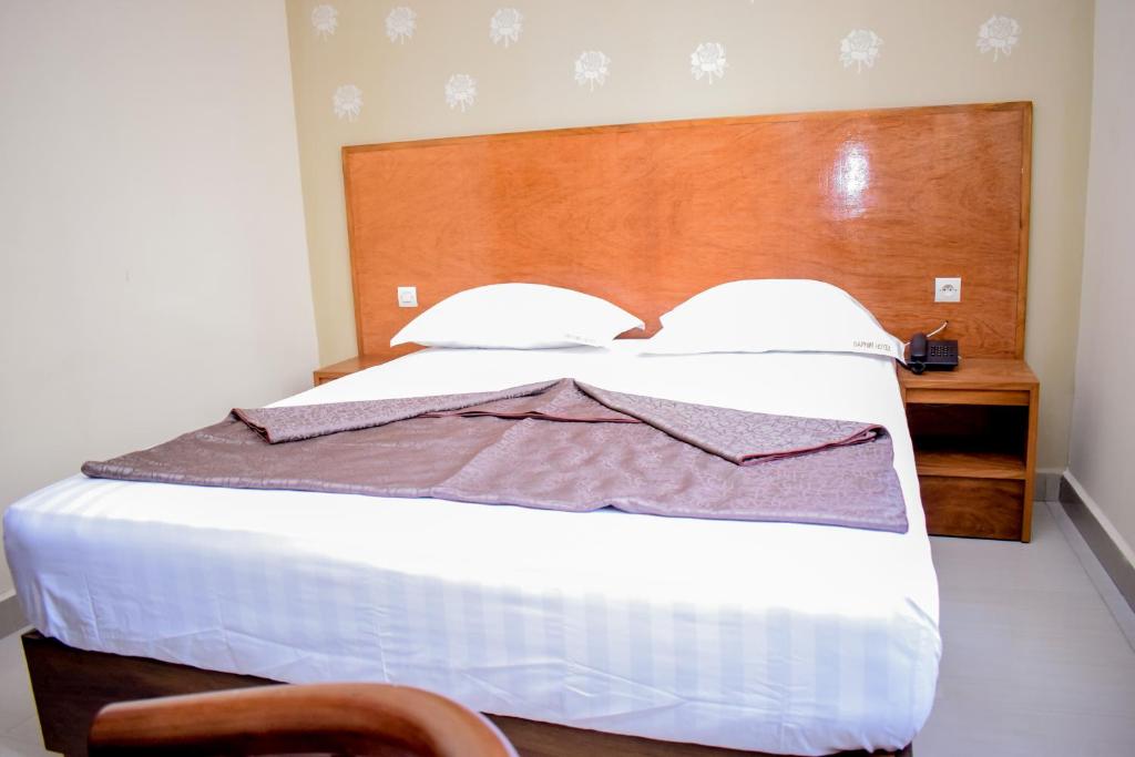 a bedroom with a large white bed with a wooden headboard at Saphir hotel in Kinshasa