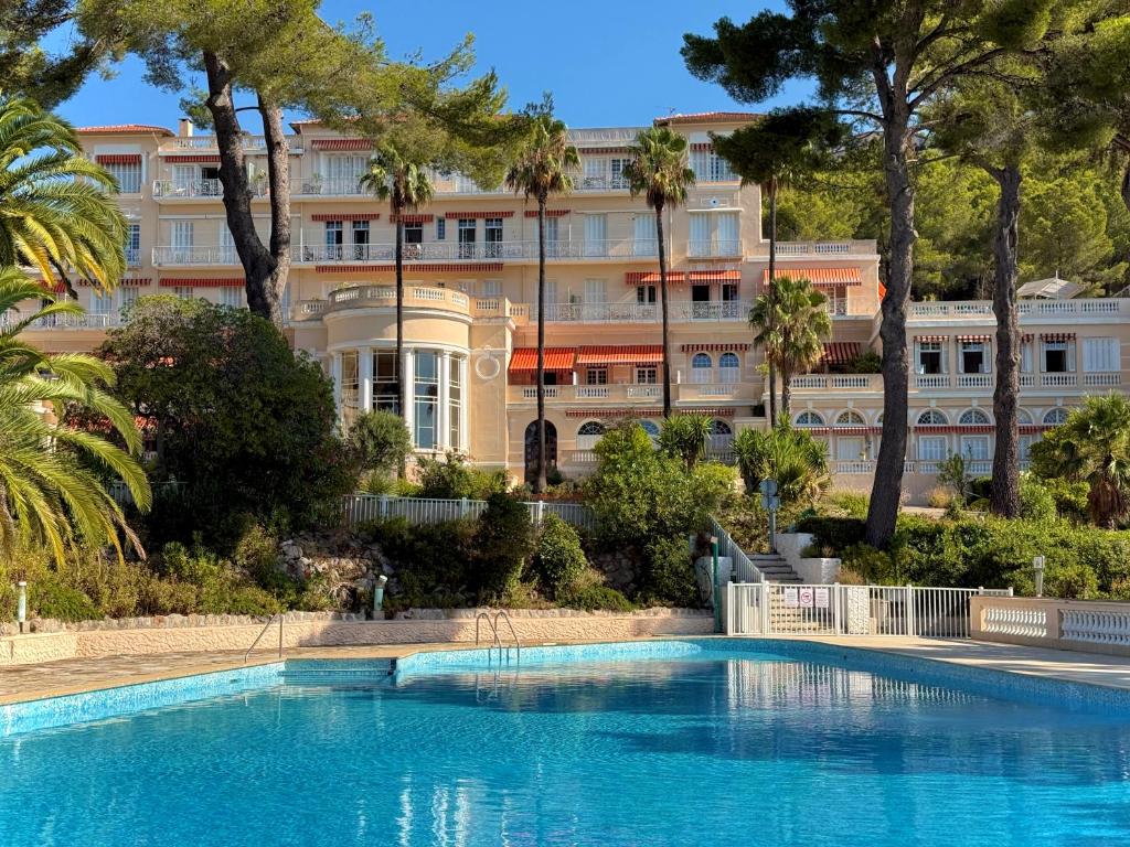 a hotel with a swimming pool in front of a building at La Boîte Rose - Studio plage de l'Almanarre in Hyères