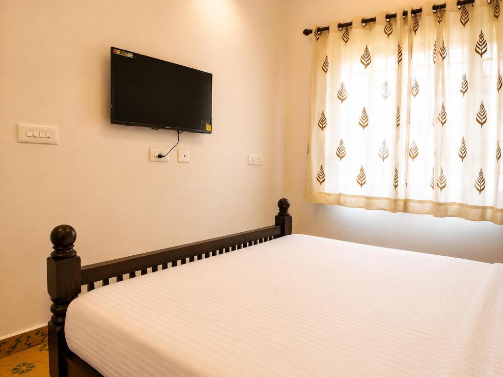a bedroom with a bed with a flat screen tv on the wall at Vox Valavan in Mayiladuthurai