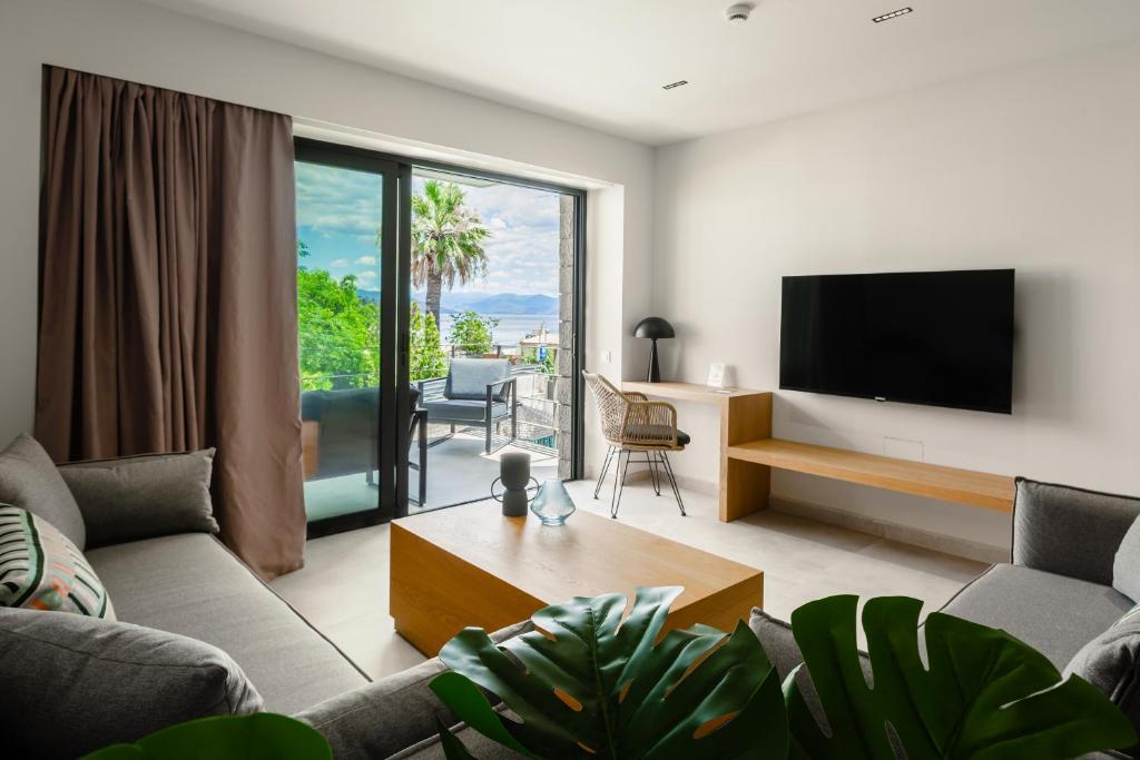 a living room with a couch and a tv at Petra Suites Tolo in Tolo