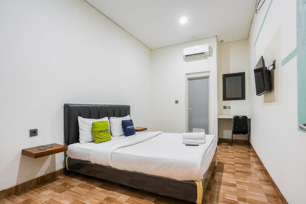 a bedroom with a large bed and a tv at Urbanview Hotel Aloevera Pontianak by RedDoorz in Pontianak