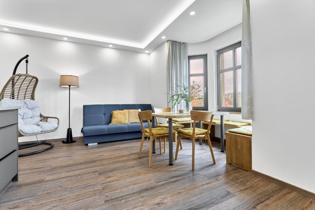 a living room with a blue couch and a table and chairs at Apartmány s výhledem na Plešivec by Mountain ways in Abertamy