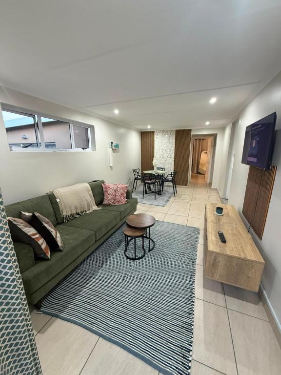 a living room with a green couch and a table at Cambridge Boutique Stay in Chiselhurst