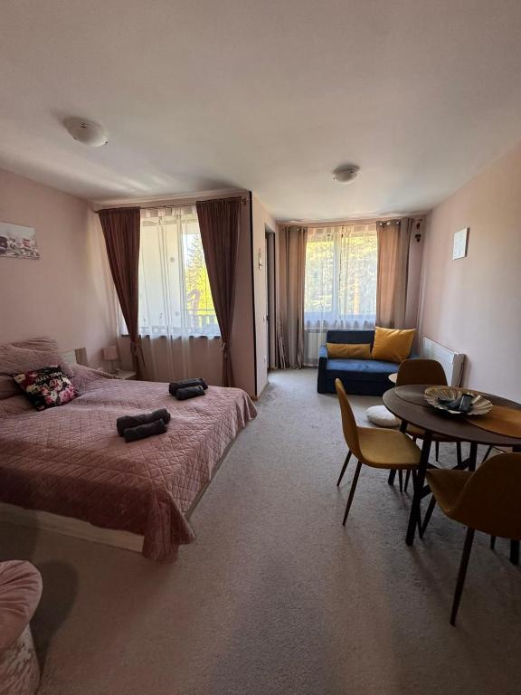 a bedroom with two beds and a table and a couch at MVS Borovetz Gardens Apart E28 studio in Borovets