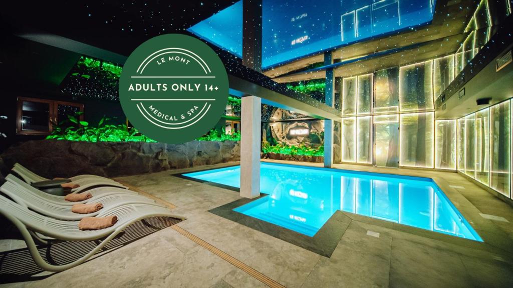 a swimming pool with lounge chairs next to a building at Hotel Le Mont Medical & SPA Adults Only in Świeradów-Zdrój