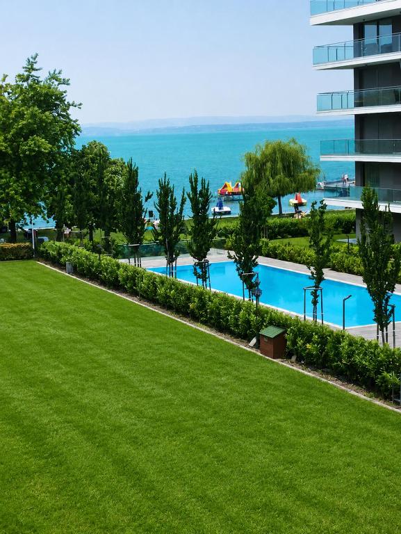 a lawn in front of a building with a swimming pool at Sunrise Apartman in Siófok