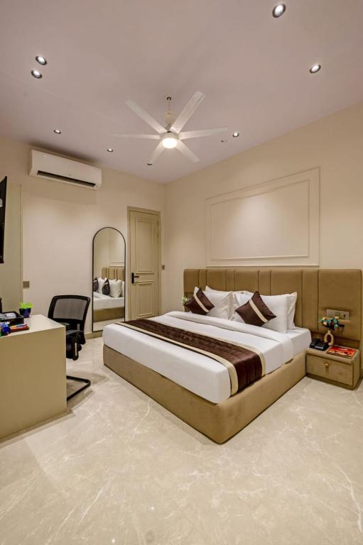 a bedroom with a large bed and a desk at Hotel Grand Elite- Ghaziabad in Ghaziabad