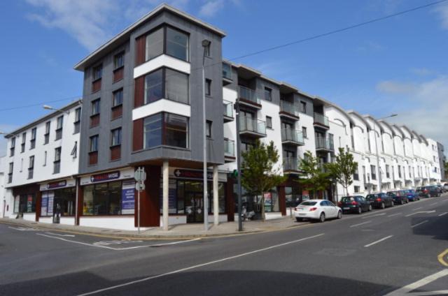 een groot gebouw in een stadsstraat met geparkeerde auto's bij Milligan Court Townhouses in Sligo