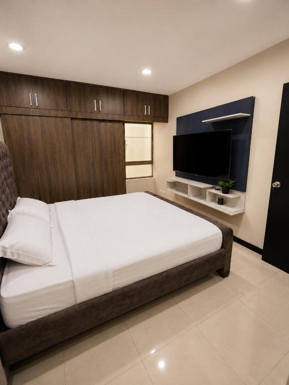 a bedroom with a large bed and a flat screen tv at Gran Propiedad en Guayaquil in Guayaquil