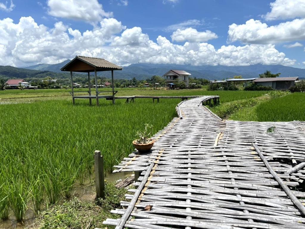 a wooden walkway in a field with a gazebo at บ้านมาดีโฮมสเตย์ in Ban Huai La