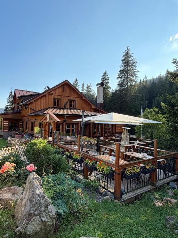 a large wooden building with tables and a fence at bouda Pod Sněžkou in Pec pod Sněžkou